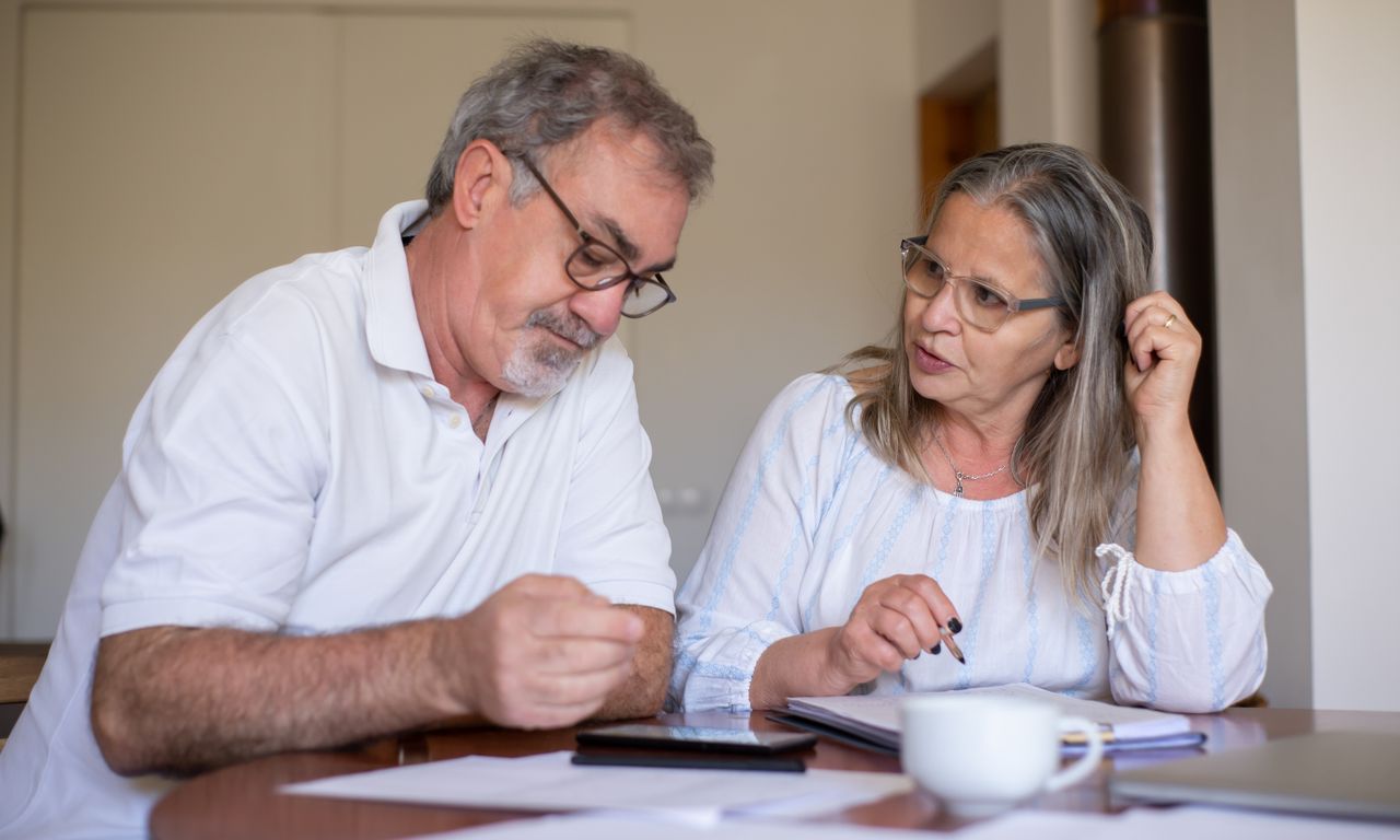 Couple in their fifties reviewing retirement and financial planning documents together at home.